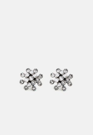 Paire de boucles d'oreilles clous ton argent avec plusieurs cristaux ronds transparents disposés en forme florale groupée sur fond blanc.