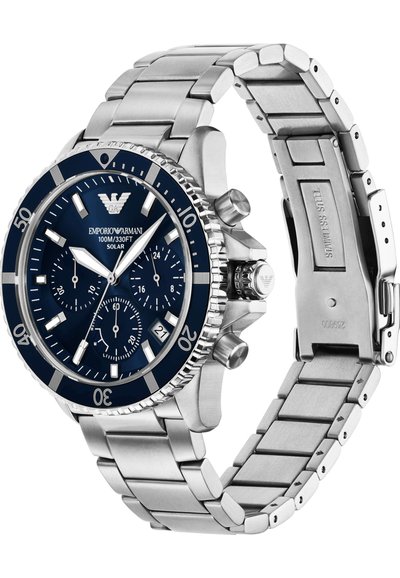 Stříbrný nerezový hodinky s modrým ciferníkem, třemi subciferníky, texturovaným lunetou a náramkem s články. Voděodolné do hloubky 100 m.