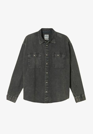 Tummanharmaa farkkupaita, jossa pitkät hihat, napit edessä, kaksi rintataskua ja tikatut yksityiskohdat kauluksen ja kalvosimien reunoilla.