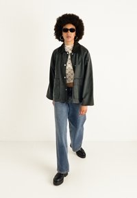 Juoda dirbtinė odos striukė, trumpas raštuotas treneris, šviesiai mėlyni plačiakojai džinsai ir platforminės bateliai, su apvaliais saulės akiniais ir auskarais-žiedais.