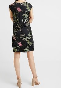 Czarna sukienka z kwiatowymi wzorami w kolorze różowym, białym i zielonym. Gładki materiał, krótkie rękawy, luźny krój, długość do kolan z okrągłym dekoltem.