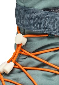 Gros plan d’une botte en tissu gris avec des lacets élastiques orange passés à travers des attaches en plastique blanc et une bride de marque gris foncé.