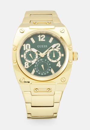 Montre en acier inoxydable doré avec un cadran vert, de grands numéraux blancs, plusieurs sous-cadrans et un bracelet à maillons.