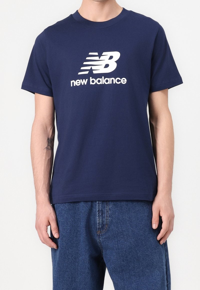 Námořnická modrá bavlněná tričko s bílým logem New Balance, krátké rukávy, kulatý výstřih a volný střih. Jednoduchý, čistý design.