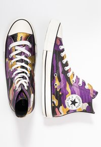 Wysokie trampki w wielokolorowy wzór fioletowy, czarny i złoty, z białymi sznurowadłami i gumową podeszwą. Oferują charakterystyczną naszywkę z logo gwiazdy po bokach.