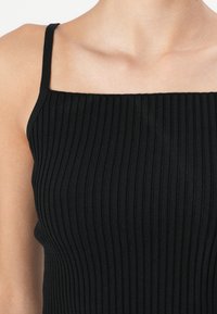 Schwarzes geripptes Tanktop mit dünnen Trägern, quadratischem Ausschnitt und taillierter Silhouette, gefertigt aus einem weichen, dehnbaren Stoff.