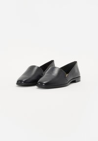 Svarte skinn slip-on sko med spiss tå og minimalistisk design. Flat hæl, jevn tekstur, og ingen synlige dekorasjoner.
