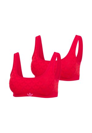 Twee rode sportbeha's met brede bandjes, subtiele reliëfpatronen en een klein wit Adidas-logo op de voorband.