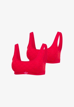 Zwei rote Sport-BHs mit breiten Trägern, dezenten geprägten Mustern und einem kleinen weißen Adidas-Logo auf dem vorderen Bund.