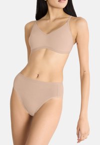 Beige saumaton rintaliivimalli säädettävillä olkaimilla ja vastaavilla korkeavyötäröisillä alushousuilla. Sileä pinta ja yksinkertainen, minimalistinen muotoilu.