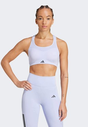 Sutien sport de culoare violet deschis, cu un design tip racerback, realizat dintr-un material respirabil. Are logo-ul negru Adidas pe față.