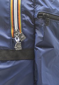 Giacca navy con doppie cerniere e finiture in argento, accento a righe multicolori sul davanti e tessuto in nylon texturizzato.