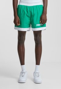 Grønne atletiske shorts med en hvid og grå kant, der har en elastisk talje og et "STARTER" logo i hvidt på venstre ben.