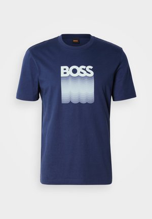 T-shirt de algodão azul marinho com o texto "BOSS" em branco, com um padrão de ondas em gradiente por baixo. Mangas curtas e decote redondo.