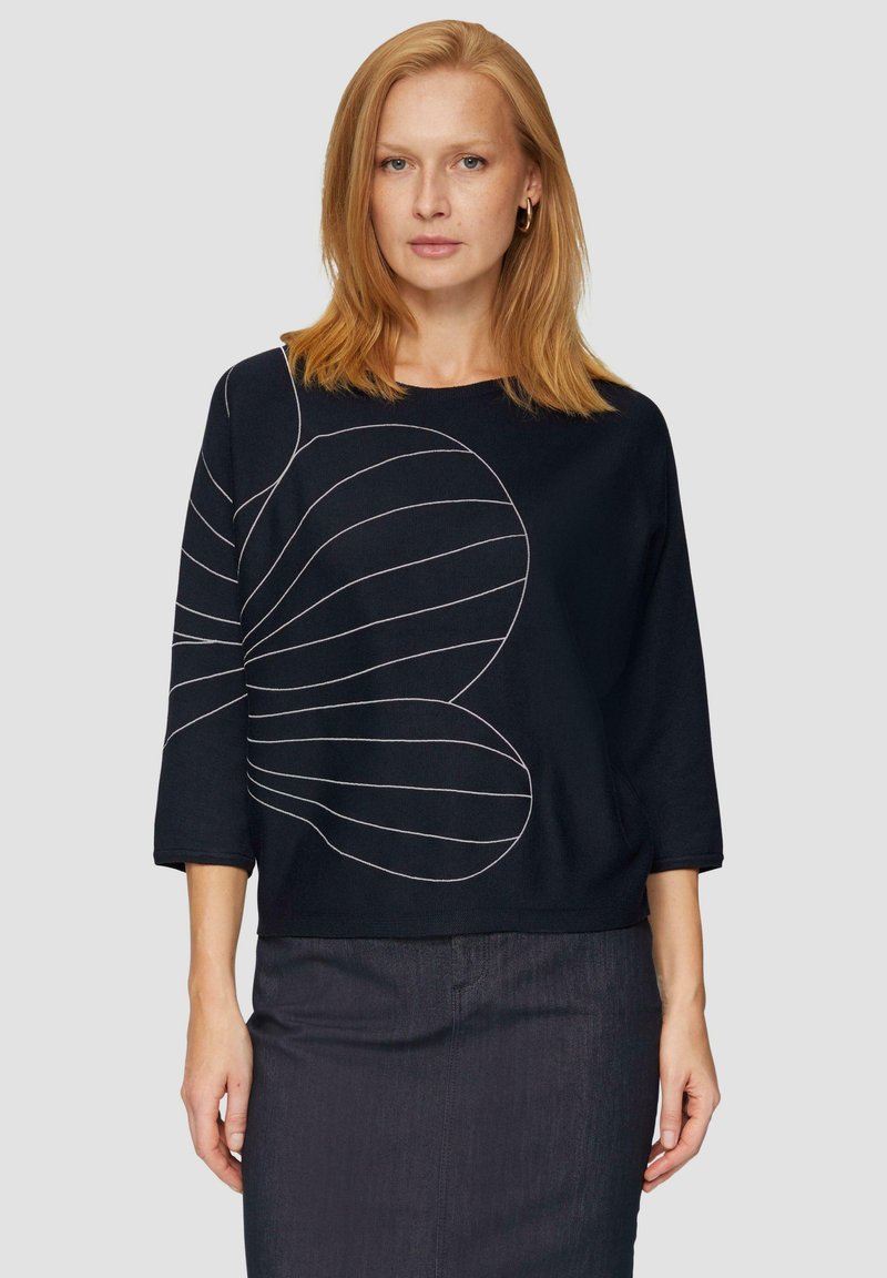 Czarna bluzka z 3/4 rękawami, z białym liniowym wzorem. Wykonana z teksturowanej tkaniny, ma luźny krój i zaokrąglony dół.