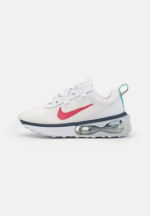 White Nike running shoe with red swoosh, transparent air cushion sole, and blue and yellow heel pull tab, side view on white background.