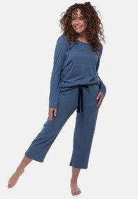 Sininen pitkähihaisten yläosan ja lyhyiden housujen setti pehmeästä kankaasta, jossa on nyöritasku ja rento istuvuus. Suunniteltu mukavuutta ja helppoa liikkuvuutta varten.