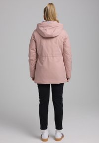 Gevoerde roze jack met een capuchon, met een rechte snit. Gepaard met zwarte pantalons en witte sneakers, met een gladde textuur en een minimalistisch ontwerp.
