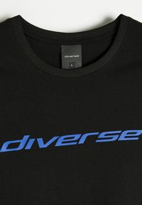 Czarny bawełniany T-shirt z okrągłym dekoltem, z niebieskim napisem "diverse" na przodzie, wydrukowanym w odważnej, nowoczesnej czcionce. Widoczna etykieta rozmiaru.