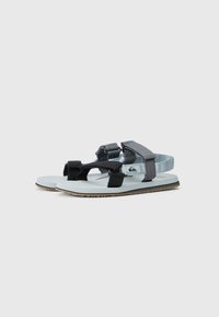Sandales noires et bleu clair avec des brides réglables, semelles texturées et un détail de logo. Design plat avec une adhérence robuste pour la stabilité.