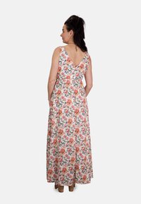 Vestido maxi de algodón floral con fondo blanco, que presenta un diseño de espalda en V, patrones vibrantes de flores naranjas y rosas, y bolsillos laterales.