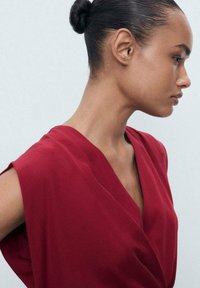 Red wrap dress with short sleeves, made from smooth fabric, featuring a V-neckline and a structured silhouette. Clean lines and minimal design.