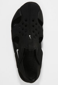 Zapatilla deportiva negra con un upper transpirable y texturizado que presenta múltiples orificios de ventilación y un diseño elegante. Logotipo de Nike en blanco.