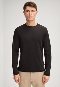 Langärmliges schwarzes T-Shirt aus leichtem Stoff. Hat einen runden Ausschnitt und ein kleines Logo auf der Brust. Einfaches, tailliertes Design.