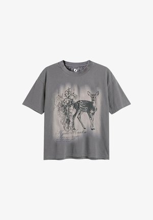 Szary t-shirt z krótkim rękawem z czarno-białą ilustracją jelenia i skomplikowanymi kwiatowymi wzorami, zawierający tekst "Mystic Meadow."