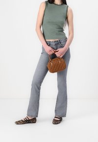 Sac à main matelassé marron avec base ronde et poignées supérieures, chemise sans manches à rayures vertes, jean gris évasé, et ballerines noires à imprimé léopard.
