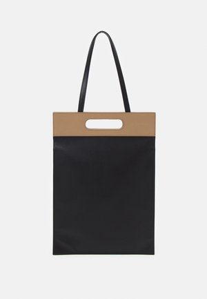 Sac cabas rectangulaire noir avec bord supérieur beige doté d'une poignée découpée et de longues fines bretelles noires.