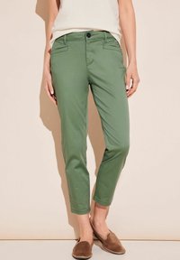 Pantalons verts en mélange de coton avec une coupe slim et une longueur cheville. Comprend deux poches avant et une fermeture à bouton. Texture lisse.