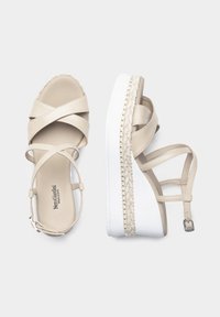 Beige platform sandaler med krydset remme, en espadrille-stil jute accent rundt om sålen og en hvid gummibase. Justerbar ankelrem.