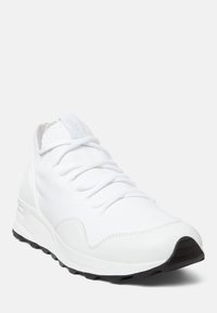 Chaussure de sport blanche en maille et matériaux synthétiques, avec un bout rond, des lacets et une semelle en caoutchouc noire. Design minimaliste.