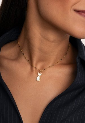 Collana d'oro con perle nere che presenta un pendente a silhouette di gatto bianco. La catena è delicata con dimensioni delle perle alternate per aggiungere texture.