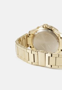 Orologio in acciaio inox dorato con una finitura liscia e lucida. Presenta un bracciale a maglie robuste e una cassa rotonda con pulsanti sul lato.