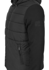 Black puffer jacket with a zippered side pocket, featuring a quilted texture on the front and smooth sleeves, includes a hood and branding detail.