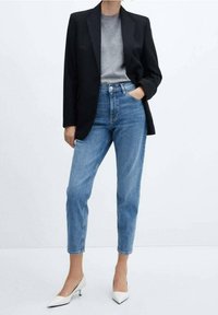 Black blazer over a gray t-shirt, paired with light blue jeans and white pointed-toe heels. The jeans feature a high waist and relaxed fit.