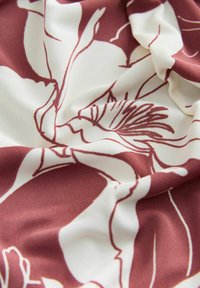 Stof met bloemenpatroon, grote witte bloemen op een mahonierode achtergrond, met een gladde, zachte textuur en een delicate val.