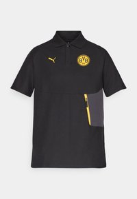 Sort polo-shirt lavet af åndbart materiale, med et gult BVB-logo, gul Puma-emblem og en grå lynlåslomme på venstre side.