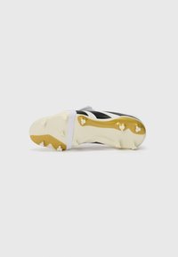 Des crampons noirs avec des rayures blanches, dotés d'un dessus texturé et d'une semelle accentuée en or. Fond clouté pour une meilleure traction sur les surfaces herbeuses.