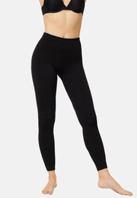 Leggings negros de tela elástica, con una cintura alta y un ajuste ceñido, sin patrones ni acentos visibles.
