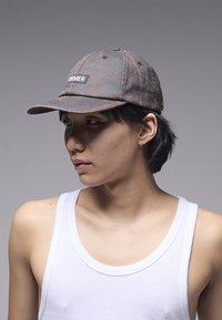 Șapcă gri cu textură uzată, având o patch neagră cu inscripția "FORMER". Vizieră curbată și design cu șase paneluri, prevăzută cu orificii de ventilație.