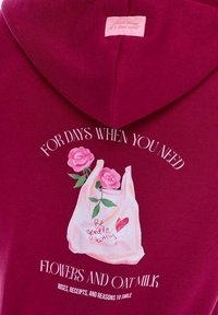 Bordový mikina s grafikou tašky na nákup s růžovými růžemi, ručně psaným textem a bílým nápisem "PRO DNY, KDY POTŘEBUJETE KVĚTINY A OVSENÉ MLÉKO."
