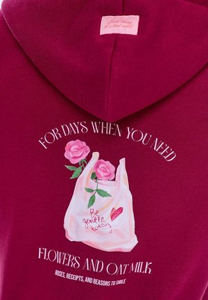 Bordový mikina s grafikou tašky na nákup s růžovými růžemi, ručně psaným textem a bílým nápisem "PRO DNY, KDY POTŘEBUJETE KVĚTINY A OVSENÉ MLÉKO."
