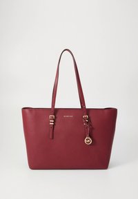Κόκκινη δερμάτινη τσάντα ώμου με διπλές λαβές, μεταλλικά στοιχεία σε χρυσό τόνο και γούρι. Διαθέτει υφή επιφάνειας και διακριτική λεπτομέρεια με λογότυπο στο μπροστινό μέρος.