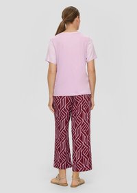 Lichtroze kortmouwen top gecombineerd met bordeaux brede broek met een geometrisch wit patroon. Effen achterkant zonder zichtbare details.