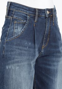 Jeans i denim i olika nyanser av blått, med hög midja, klassisk knäppning och framlomm som har kontrasterande sömmar.