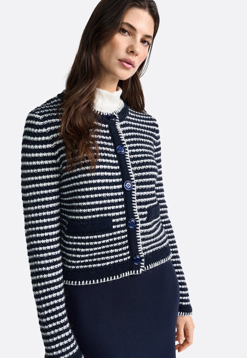 Cardigan a righe blu e bianche con scollatura rotonda, dotato di bottoni blu, due tasche frontali e un lavoro a maglia testurizzato.