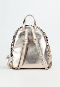 Zaino metallizzato argento con spallacci imbottiti e forma rotonda. Presenta dettagli in paillettes lungo la parte superiore e hardware in tonalità oro.